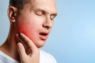 Diş ağrısı. Mavi bir arka plan bir adam yakın çekim portresi