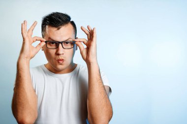 Bir yakın çekim portre gözlüklerini elleriyle düzeltiyor bir adam. Hafif bir arka plan üzerinde.