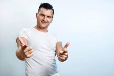Açık renkli yakın çekim bir adam portresi. Duygu önemi, kamerada silah el hareketi gösterir. Beden dili, insan duyguları, reaksiyon kavramı.