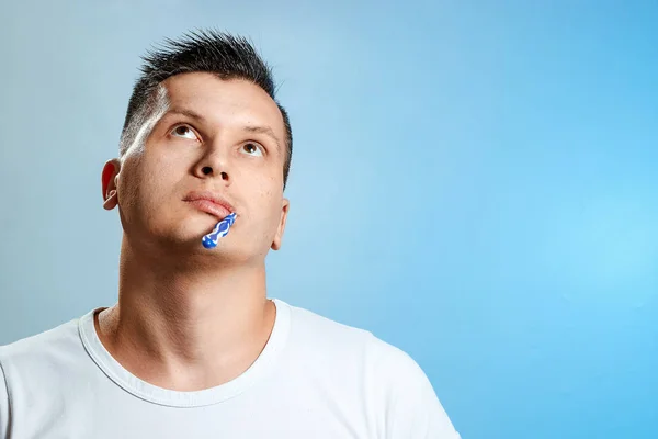 シャツを着た男は 青い背景に彼の歯を磨きます 口腔衛生の概念 — ストック写真