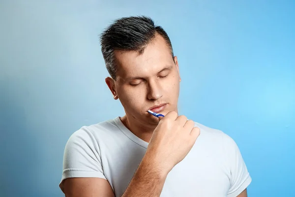 シャツを着た男は 青い背景に彼の歯を磨きます 口腔衛生の概念 — ストック写真