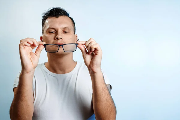 Un retrato de cerca de un hombre que endereza sus gafas con las manos. Sobre un fondo claro . — Foto de Stock