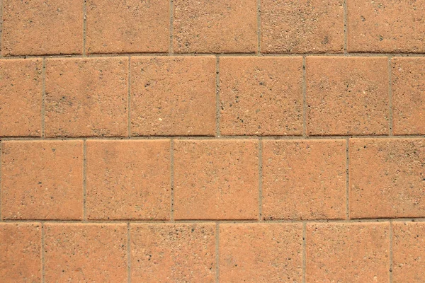 Patio paving orange tiles, stone background, wall of blocks.