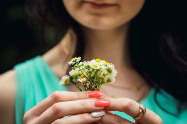 Bir kız chamomiles küçük bir buket tutuyor