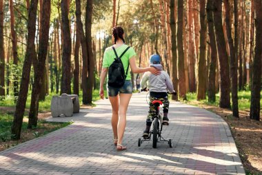 Anne oğlu parkta Bisiklete binmeyi öğretir