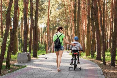 Anne oğlu parkta Bisiklete binmeyi öğretir