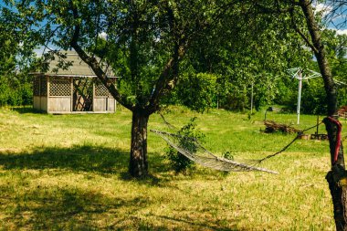 Yeşil orman hamakta ile tembel zaman dinlendirici. Hamak yaz Bahçe, güneşli gün havada sallanan ile güzel bir manzara. Seyahat, Macera, kamp malzemeleri, doğa açık havada öğeleri.