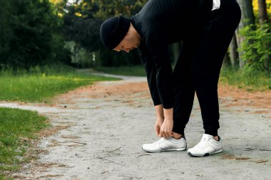 Bir adam bir yaz sabah kopya alanı üzerinde yeşil bir parkta sabah egzersiz için hazırlık egzersizleri yapıyor