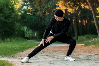 Bir adam bir yaz sabah kopya alanı üzerinde yeşil bir parkta sabah egzersiz için hazırlık egzersizleri yapıyor
