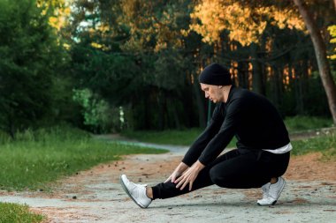 Bir adam bir yaz sabah kopya alanı üzerinde yeşil bir parkta sabah egzersiz için hazırlık egzersizleri yapıyor
