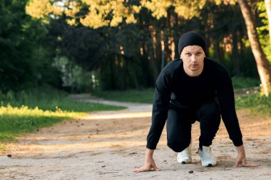 Bir adam bir yaz sabah kopya alanı üzerinde yeşil bir parkta sabah egzersiz için hazırlık egzersizleri yapıyor