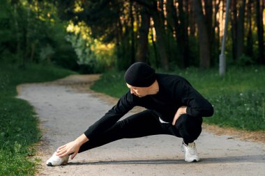 Bir adam bir yaz sabah kopya alanı üzerinde yeşil bir parkta sabah egzersiz için hazırlık egzersizleri yapıyor