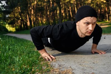 Bir adam bir yaz sabah kopya alanı üzerinde yeşil bir parkta sabah egzersiz için hazırlık egzersizleri yapıyor