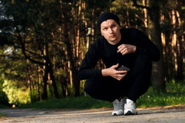 Bir adam bir yaz sabah kopya alanı üzerinde yeşil bir parkta sabah egzersiz için hazırlık egzersizleri yapıyor