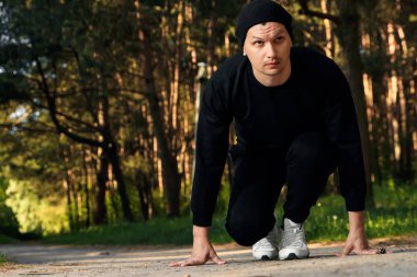 Bir adam bir yaz sabah kopya alanı üzerinde yeşil bir parkta sabah egzersiz için hazırlık egzersizleri yapıyor