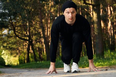 Bir adam bir yaz sabah kopya alanı üzerinde yeşil bir parkta sabah egzersiz için hazırlık egzersizleri yapıyor