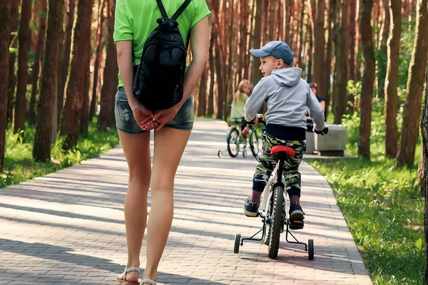 Mom teaches his son to ride a bicycle in the park