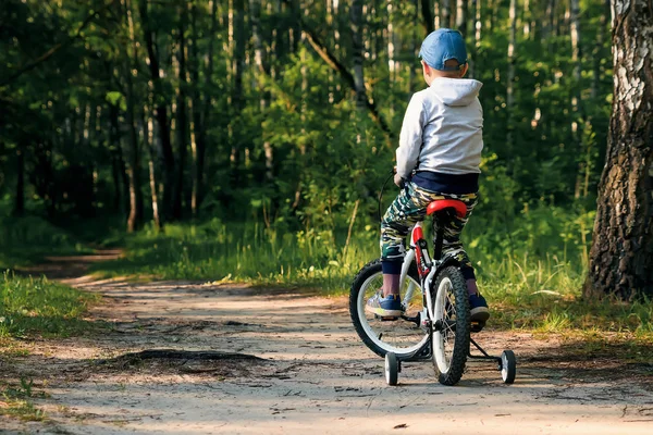 早朝に森の中で自転車に乗っている子供 男の子はヘルメットで屋外サイクリング — ストック写真