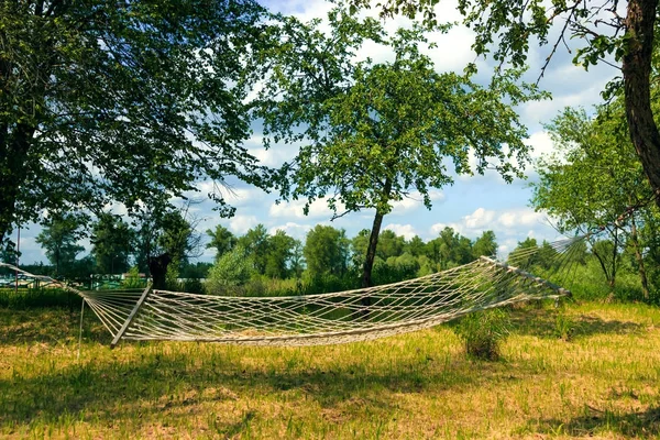 Yeşil orman hamakta ile tembel zaman dinlendirici. Hamak yaz Bahçe, güneşli gün havada sallanan ile güzel bir manzara. Seyahat, Macera, kamp malzemeleri, doğa açık havada öğeleri.