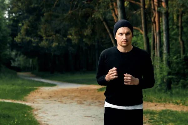 公園コピー スペースの周りを実行している黒いスポーツ スーツを着た男で朝のジョギング — ストック写真