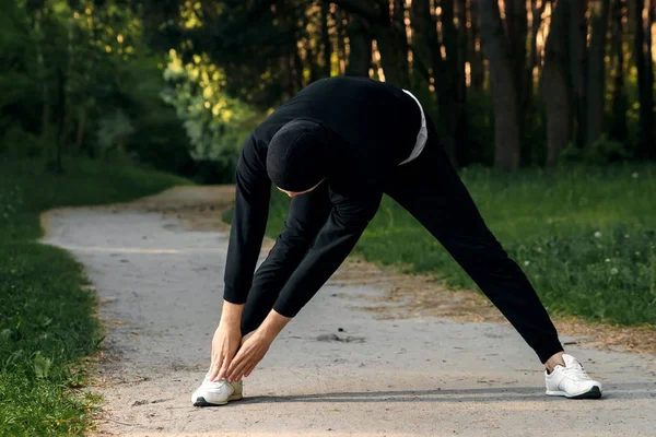 Bir adam bir yaz sabah kopya alanı üzerinde yeşil bir parkta sabah egzersiz için hazırlık egzersizleri yapıyor