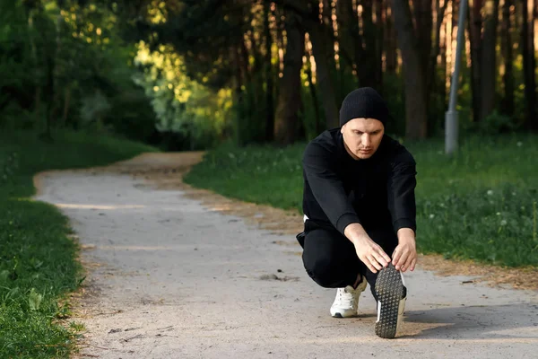 Bir adam bir yaz sabah kopya alanı üzerinde yeşil bir parkta sabah egzersiz için hazırlık egzersizleri yapıyor