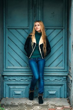 Marihuana yaprağı ağzında tutarak ve eski kapıya yaslanmış retro güneş gözlüğü takıyor şapkalı hippi sarışın kız... Yumuşak ışık, sokak stili.