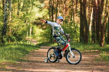 Sabahın erken saatlerinde ormanda bisiklete binen bir çocuk. Kasklı çocuk dışarıda bisiklet sürüyor.