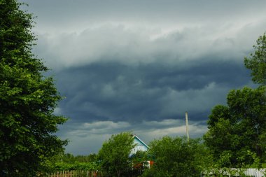 Yaz aylarında güneş ışığı ve yeşil doğa ile fırtına öncesi karanlık gökyüzü.