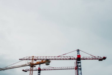 İnşaat alanı. Bitmemiş yüksek binaları ve arka planında mavi gökyüzü olan büyük endüstriyel vinçler. Darağacı. Modern inşaat mühendisliği. Çağdaş şehir manzarası.