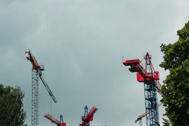 İnşaat alanı. Bitmemiş yüksek binaları ve arka planında mavi gökyüzü olan büyük endüstriyel vinçler. Darağacı. Modern inşaat mühendisliği. Çağdaş şehir manzarası.