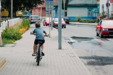 Çocuk şehirde, arkadan görünümü bir bisiklet sürme