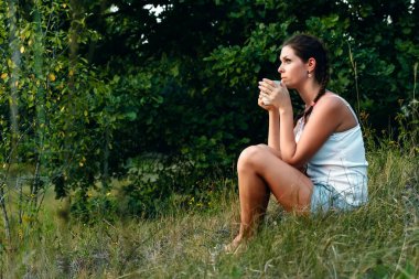 Genç bir kız kahve içer ve günbatımı, Uzaklik içinbeklediğini chesshouse. Beklenti, özlem, fantezi, rüyalar kavramı. Kopya alanı.