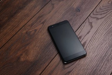 Modern bir akıllı telefon üzerinde kahverengi ahşap bir masa aittir. Kopya alanı.