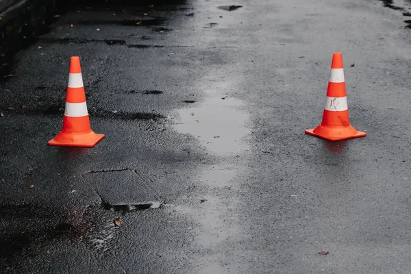 traffic cone, with white and orange stripes on gray asphalt, copy space