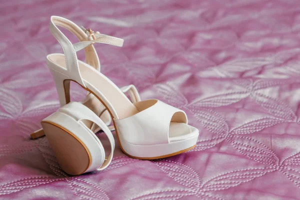 Gelinin Biege'e bir halı üzerinde topuk ayakkabılarla.