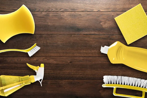 Image with various tools for cleaning the premises of yellow color on a wooden background. The concept of cleaning the premises, cleanliness.