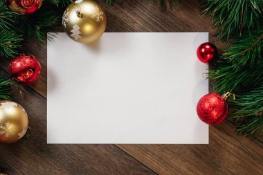 Çamın dalları ve yılbaşı süsleri ve A4 sayfa ahşap bir masa üzerinde white Paper bir çerçeve. Tatil Noel arka plan. Metin veya tasarım için alan kopyalayın. Yukarıdan görüntülemek.