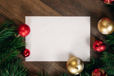 Çamın dalları ve yılbaşı süsleri ve A4 sayfa ahşap bir masa üzerinde white Paper bir çerçeve. Tatil Noel arka plan. Metin veya tasarım için alan kopyalayın. Yukarıdan görüntülemek.