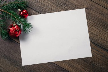 Çamın dalları ve yılbaşı süsleri ve A4 sayfa ahşap bir masa üzerinde white Paper bir çerçeve. Tatil Noel arka plan. Metin veya tasarım için alan kopyalayın. Yukarıdan görüntülemek.