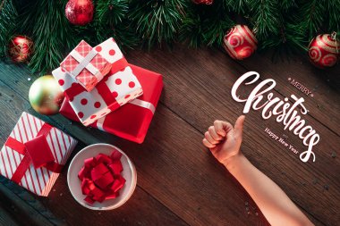 Mutlu Noeller ve mutlu yeni yıl yazıt, ahşap bir kahverengi masa üzerinde bir hediye erkek elele tutuşun. Noel kartı, tatil arka plan. Karma ortam. Yukarıdan görüntülemek.
