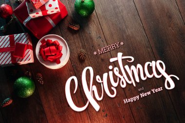 Mutlu Noeller ve mutlu yeni yıl, süslemeleri ve hediyeler ahşap bir kahverengi masa üzerinde yazıt. Noel kartı, tatil arka plan. Karışık teknik.