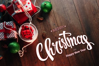 Mutlu Noeller ve mutlu yeni yıl, süslemeleri ve hediyeler ahşap bir kahverengi masa üzerinde yazıt. Noel kartı, tatil arka plan. Karışık teknik.