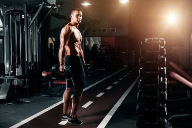 Yakışıklı olan Avrupa görünümünü vücut geliştirmeci, onun elinde dumbbells ile spor salonunda duruyor. Spor eğitim, eğitim, spor salonunda egzersiz fitness kavramı.