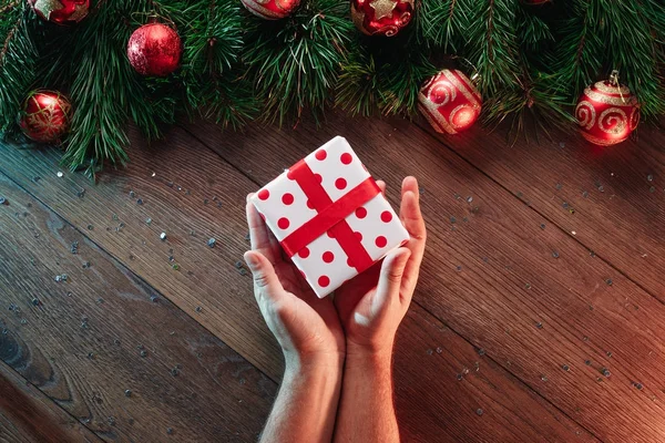 一架松树枝和圣诞装饰品 手在木桌的背景下赠送礼物 圣诞快乐 假期愉快 从上面查看 — 图库照片