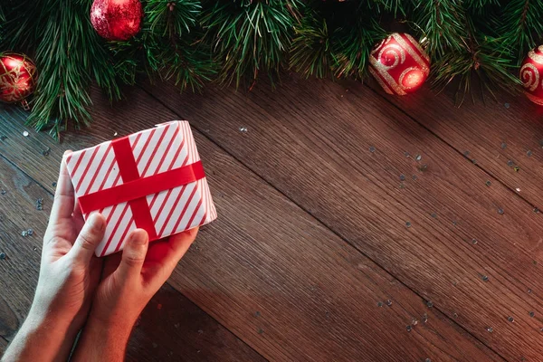 一架松树枝和圣诞装饰品 手在木桌的背景下赠送礼物 圣诞快乐 假期愉快 从上面查看 复制空间 — 图库照片