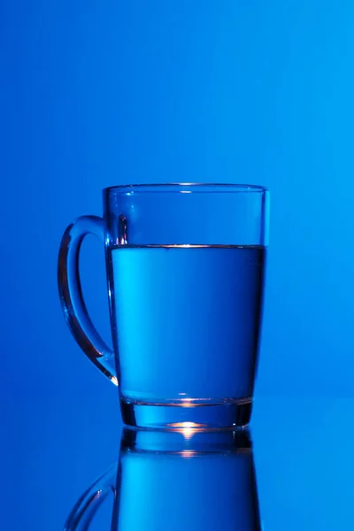 Woda Szkle Ciemnym Niebieskim Tle — Zdjęcie stockowe