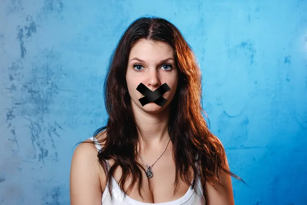 若い女性の口は ブルーの壁に黒いリボンで覆われています 家庭内暴力の概念は 彼の妻の国内の嘲笑 — ストック写真