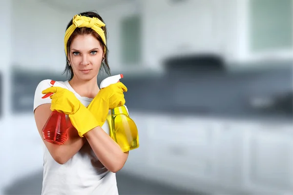 A girl, a cleaning lady with a cleanser, wearing gloves and a rag on a blue background. The concept of cleanliness in the house, cleaning of premises, cleanliness.