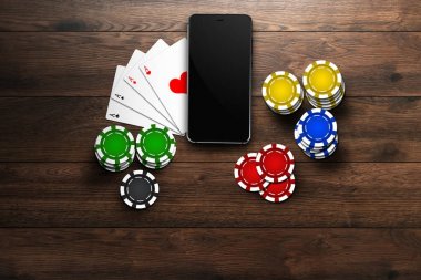 Online casino mobil casino, bir cep telefonu, en iyi görünümünü kartları bir ahşap arka plan üzerinde fişleri. Kumar Oyunları.